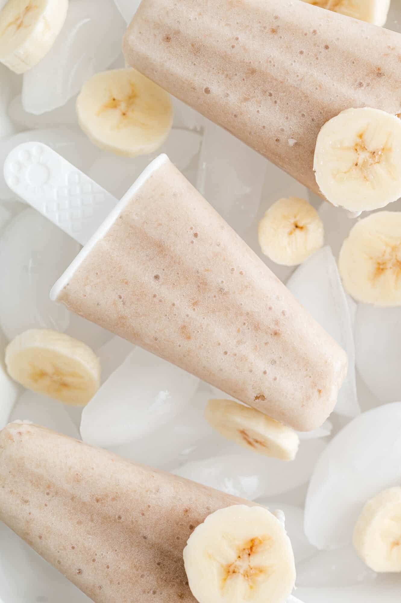 Banana popsicles with banana slices nearby.