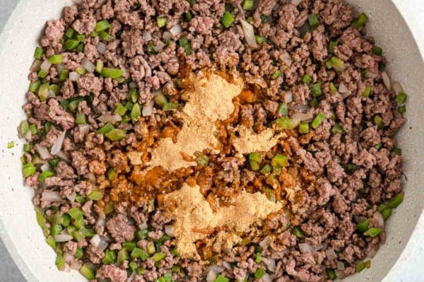 Taco seasoning added to browned ground beef in a skillet.