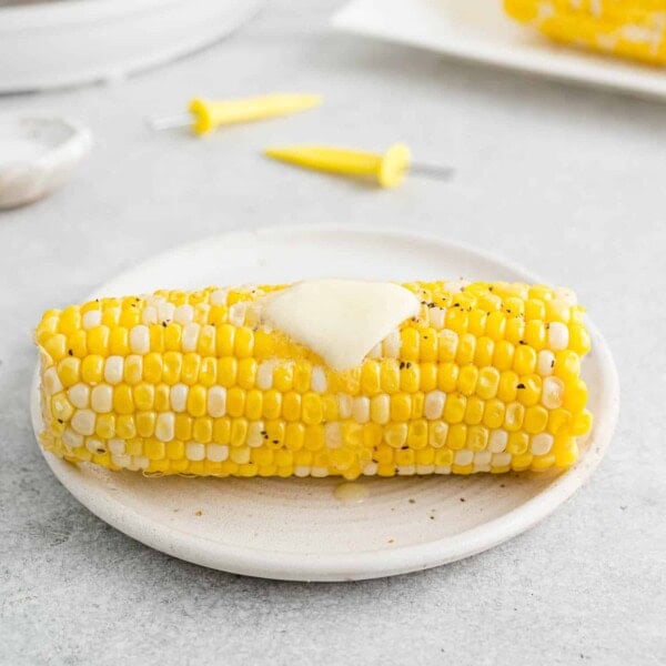 Instant pot corn on the cob on a white plate, with butter on top.
