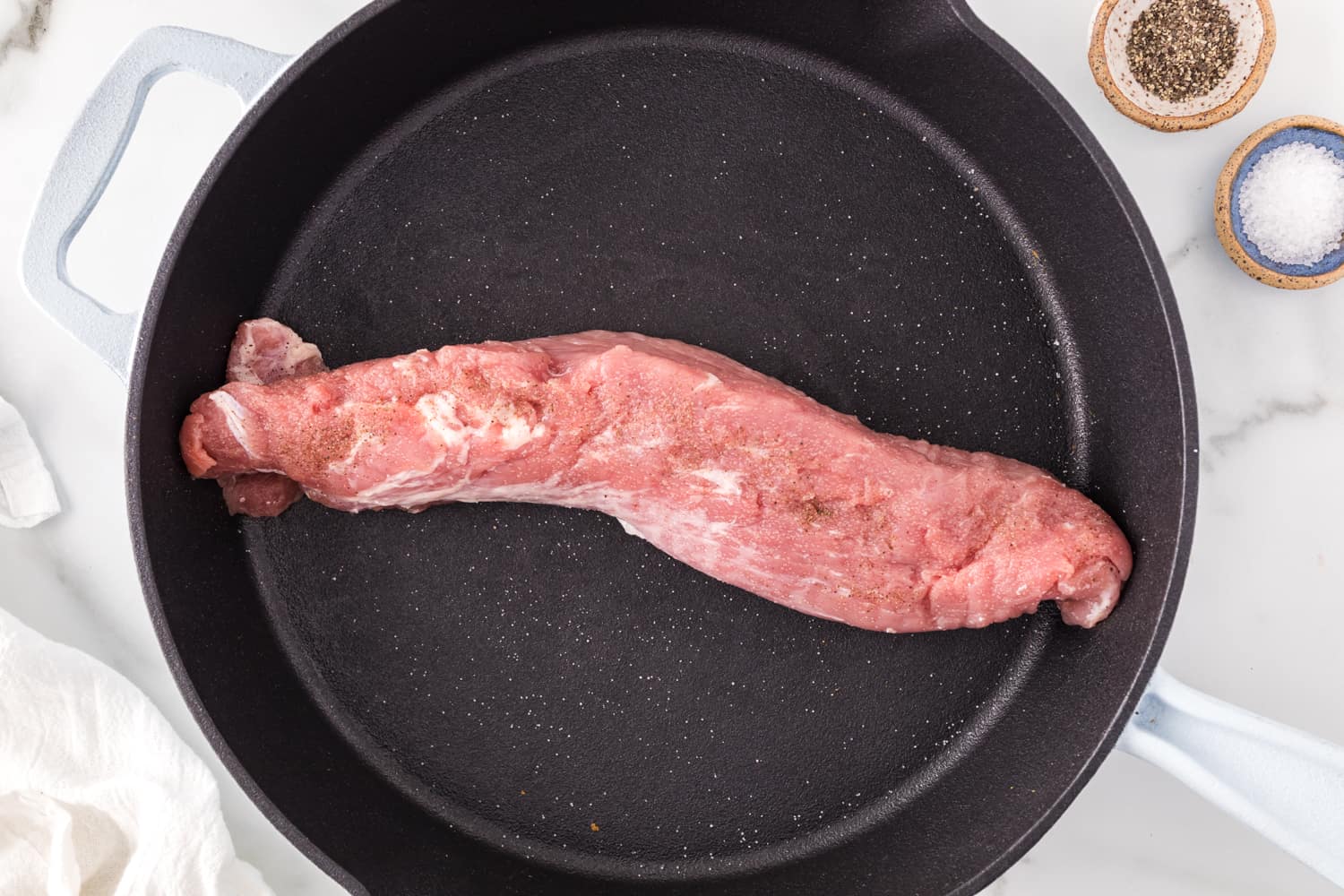 Pork tenderloin in frying pan, not yet cooked.