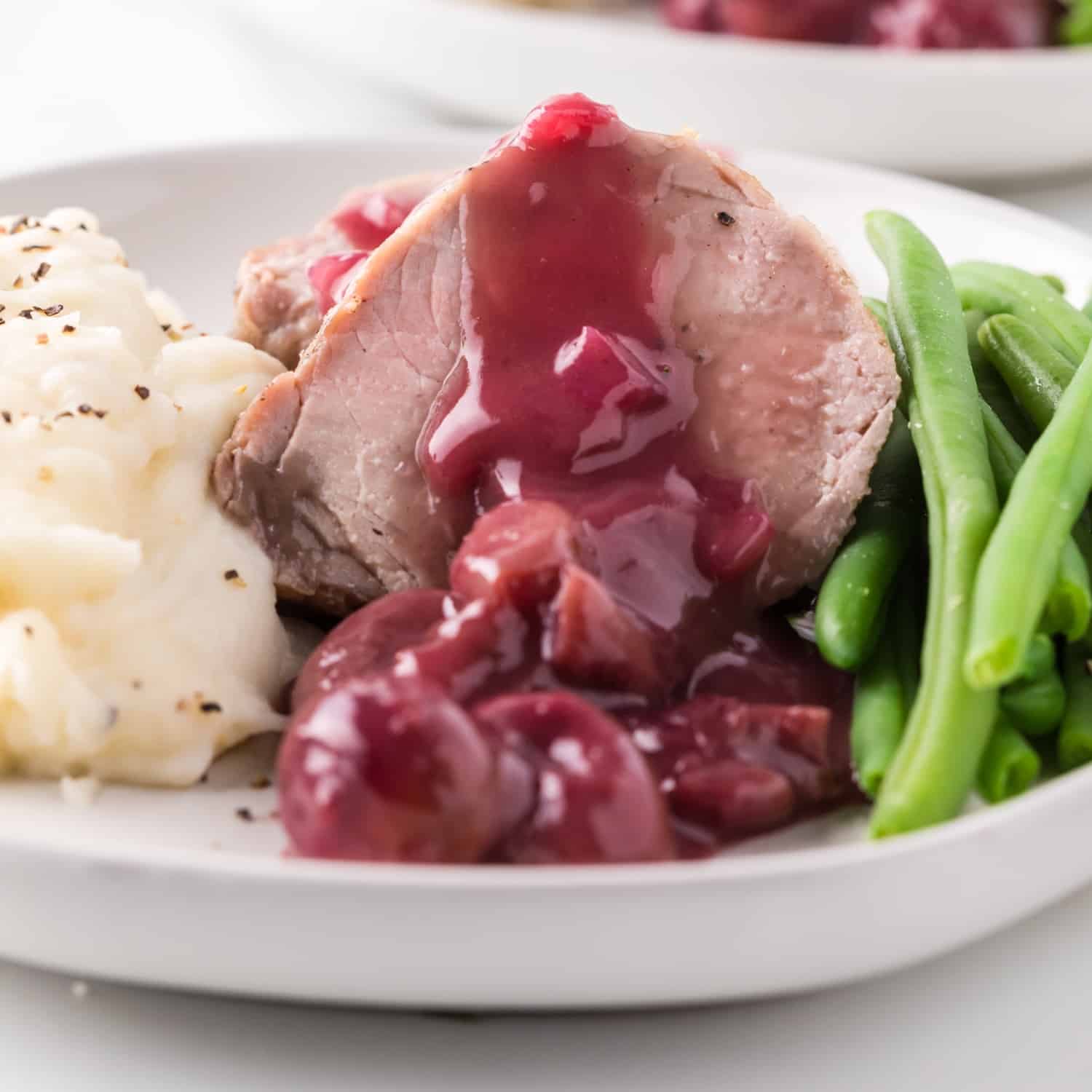 Sliced pork tenderloin with port wine sauce, roasted grapes, green beans and potatoes.