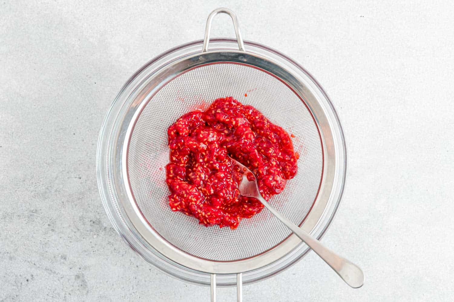 Raspberries being mashed with a fork.