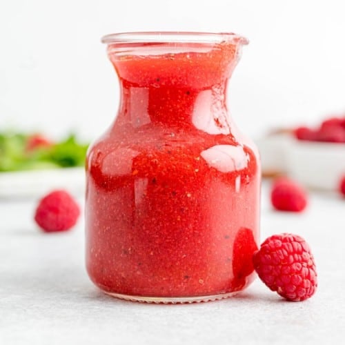 Raspberry vinaigrette in a small jar.