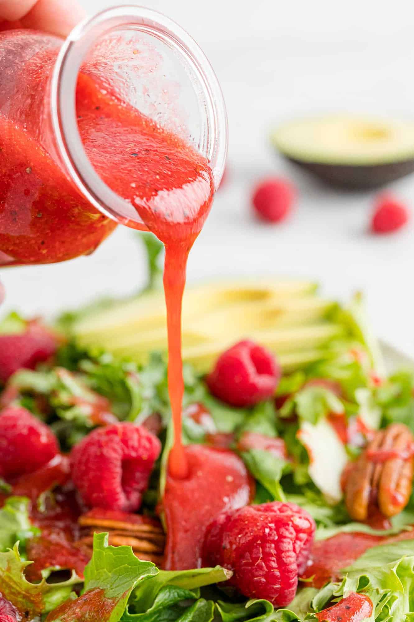 Vinaigrette dressing being poured on a salad.