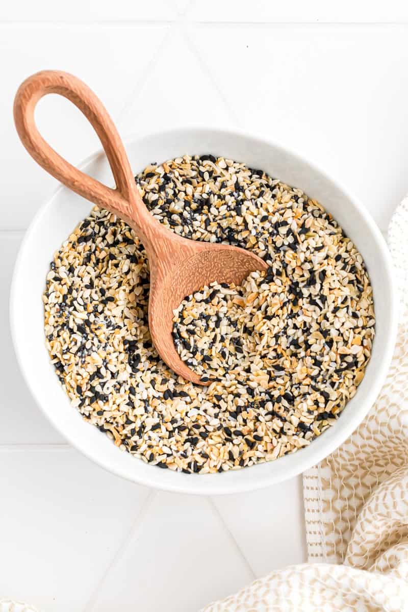 A wooden spoon in a bowl of everything bagel seasoning.