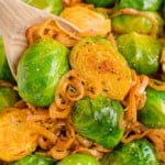 Smoky Brussels sprouts with shallots, on a wooden spoon.