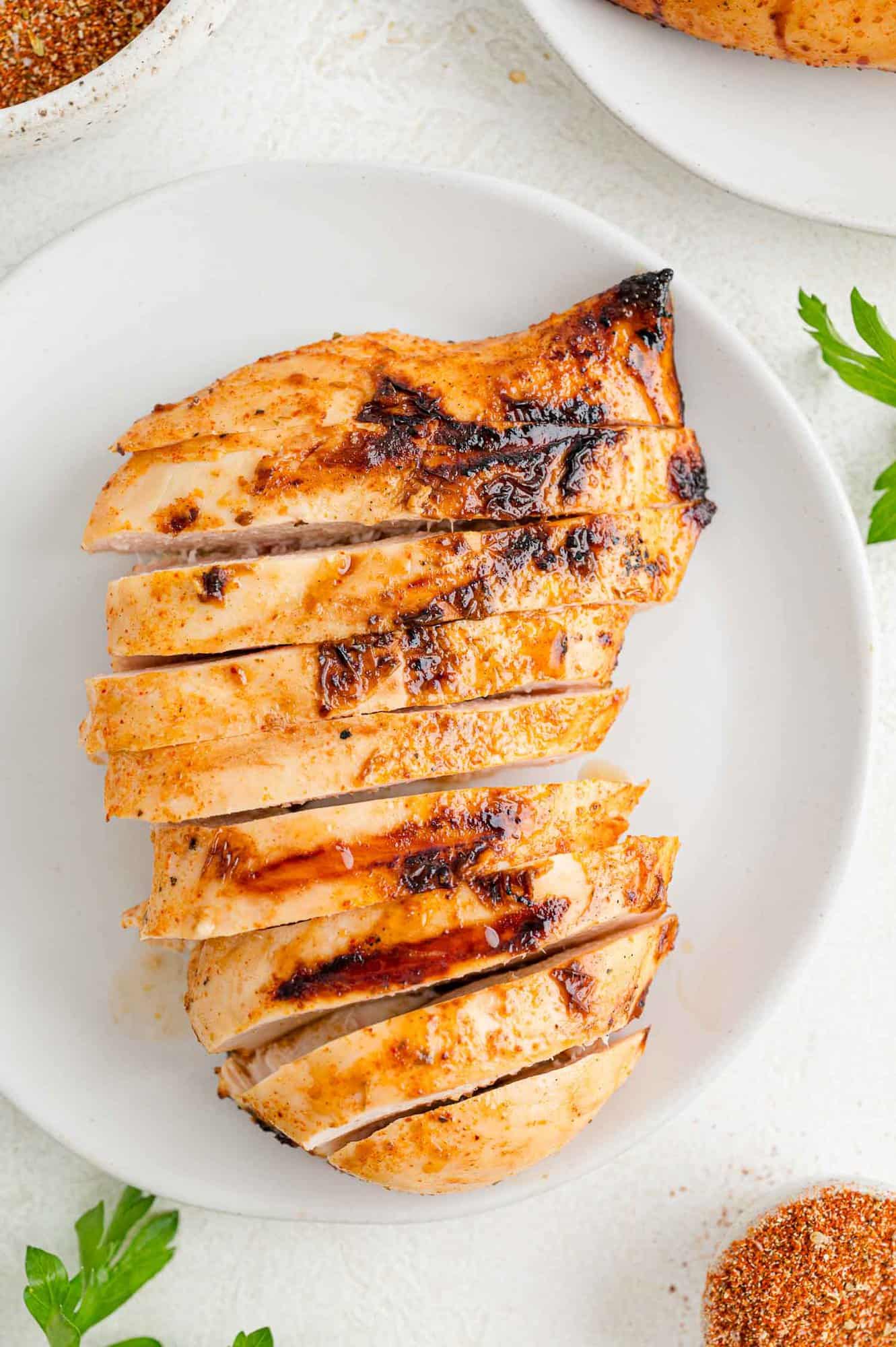 Overhead view of grilled Southwest chicken sliced on a white plate.