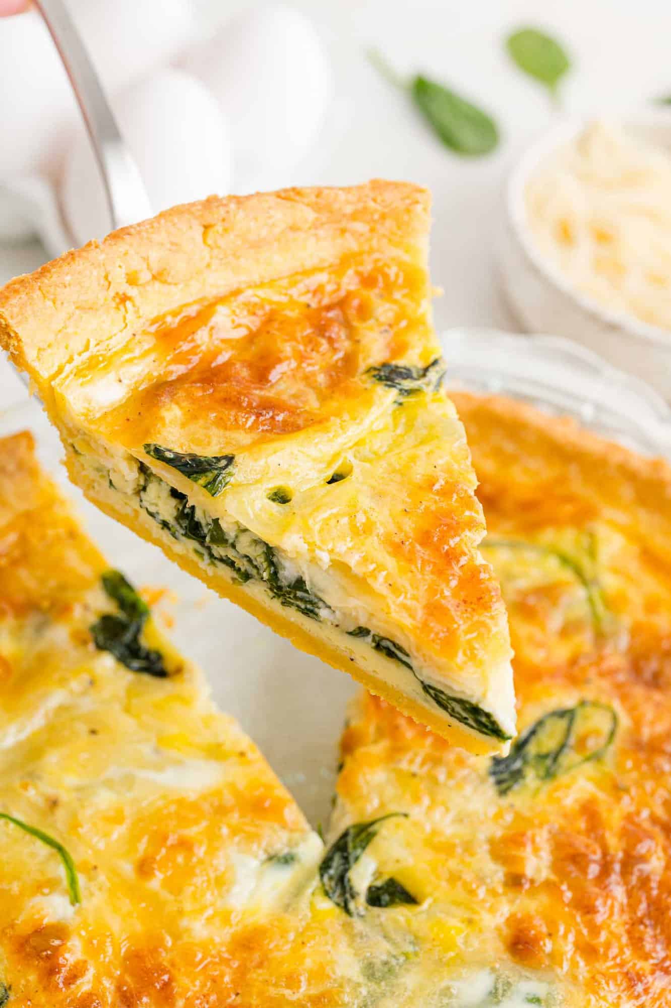 Slice of spinach quiche being served.