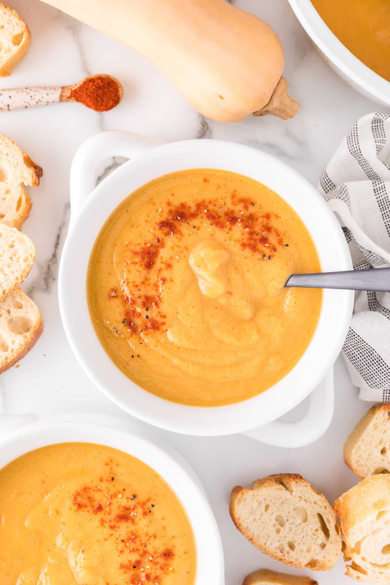 Vegan butternuts quash soup in a white bowl garnished with paprika.