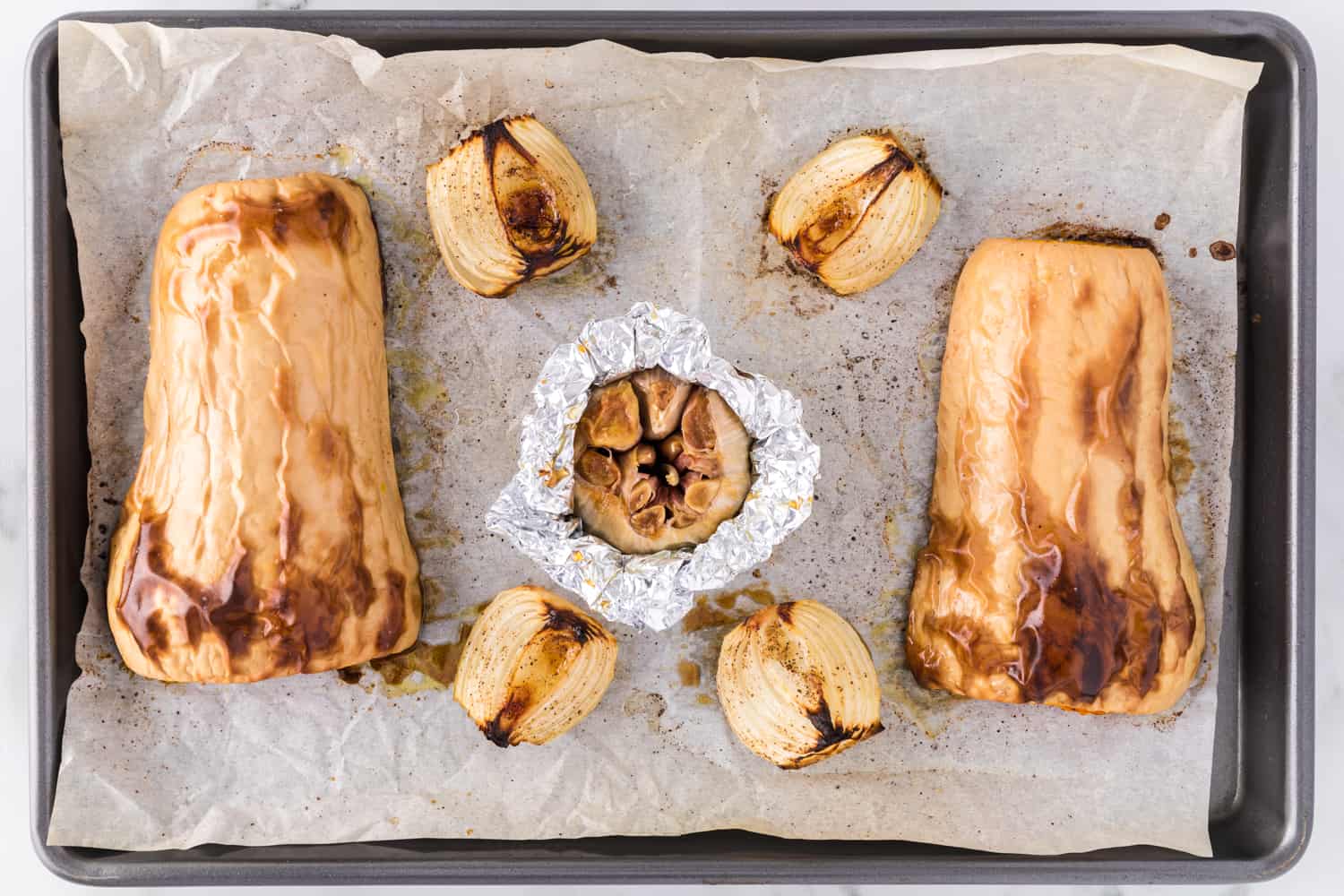 Roasted squash, onion, and garlic on a sheet pan.