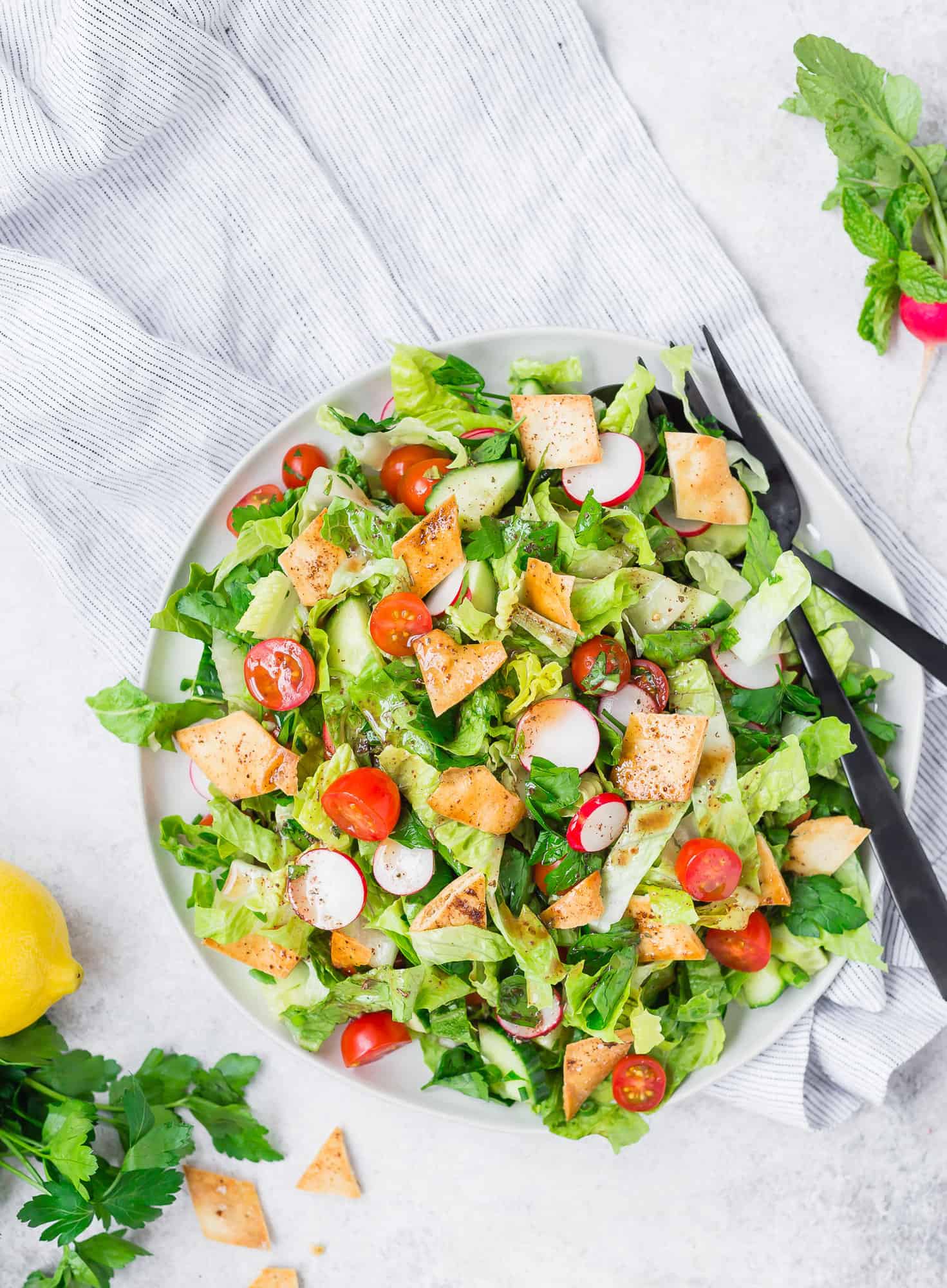 Fattoush salad on large serving platter with black utensils.