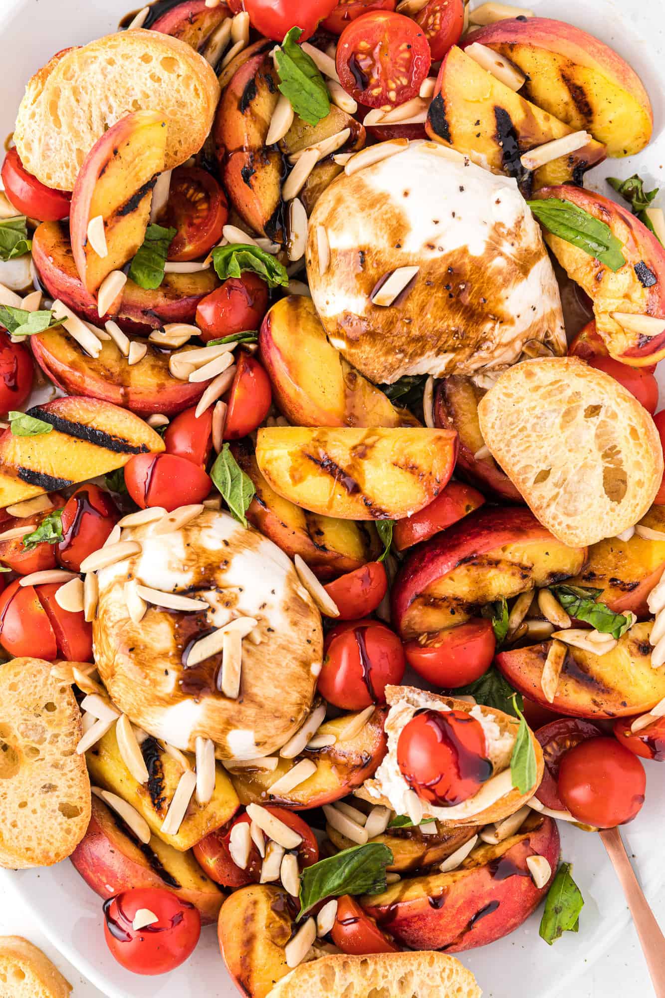 Grilled peach salad with tomatoes, with crostini for serving.