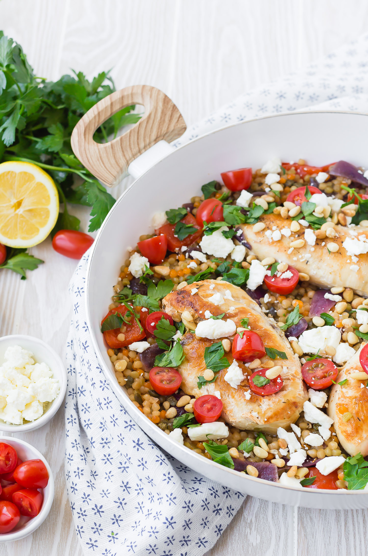 Mediterranean chicken and pearl couscous in a white skillet.