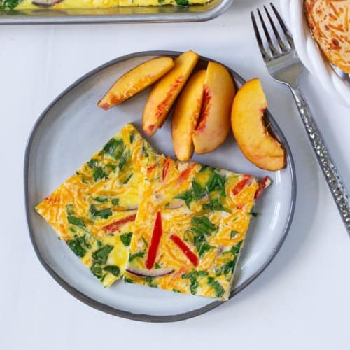 Sheet pan eggs served on a plate with fresh peaches.