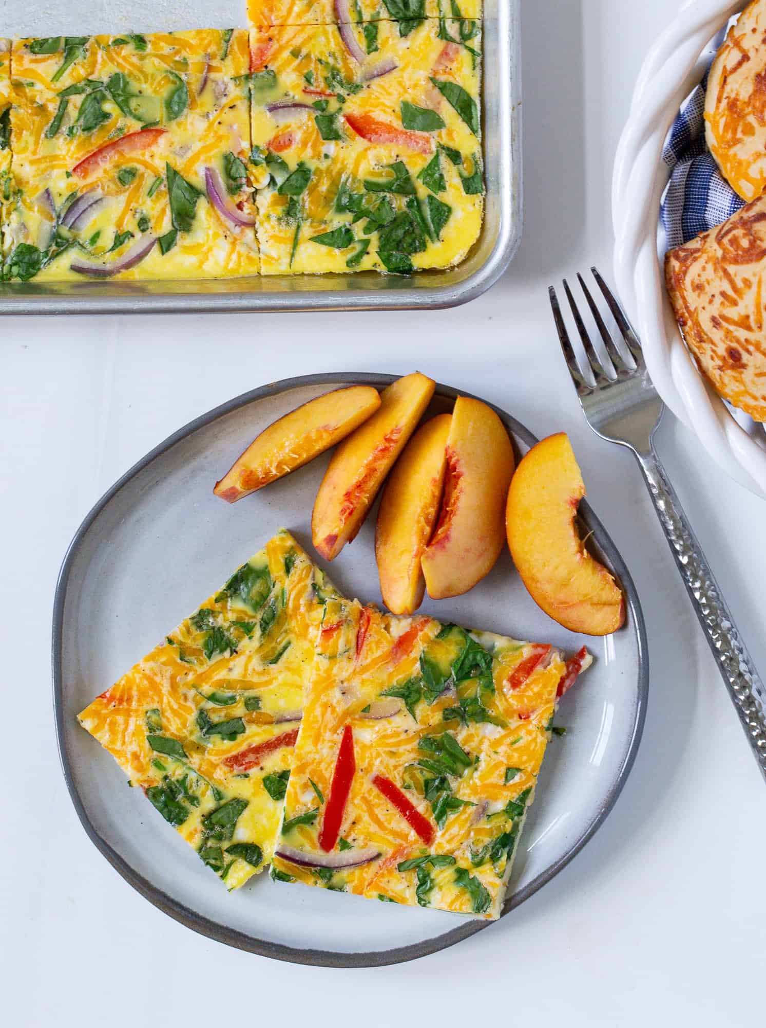 Sheet pan eggs served on a plate with fresh peaches.