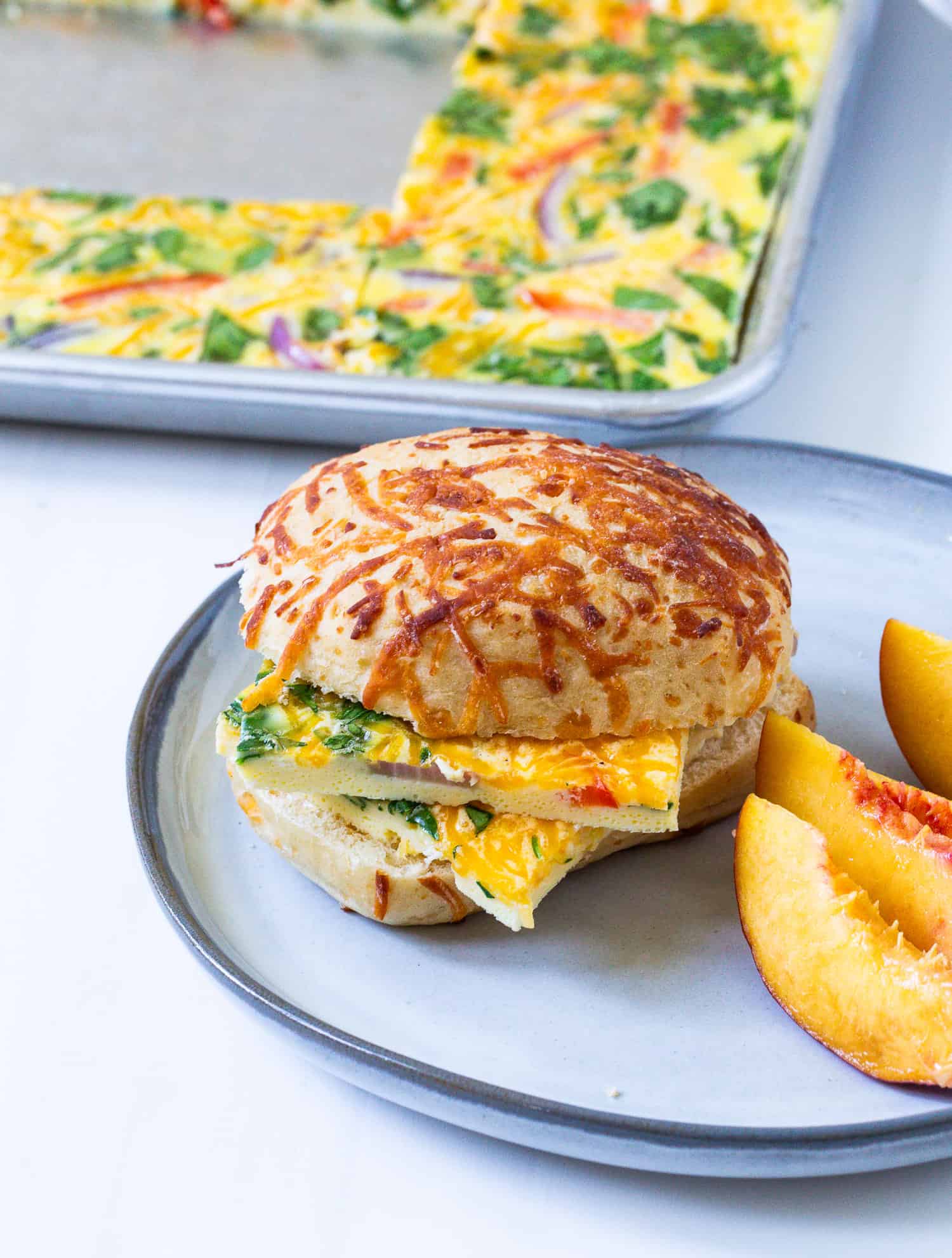 Sheet pan scrambled eggs served on a cheesy roll.