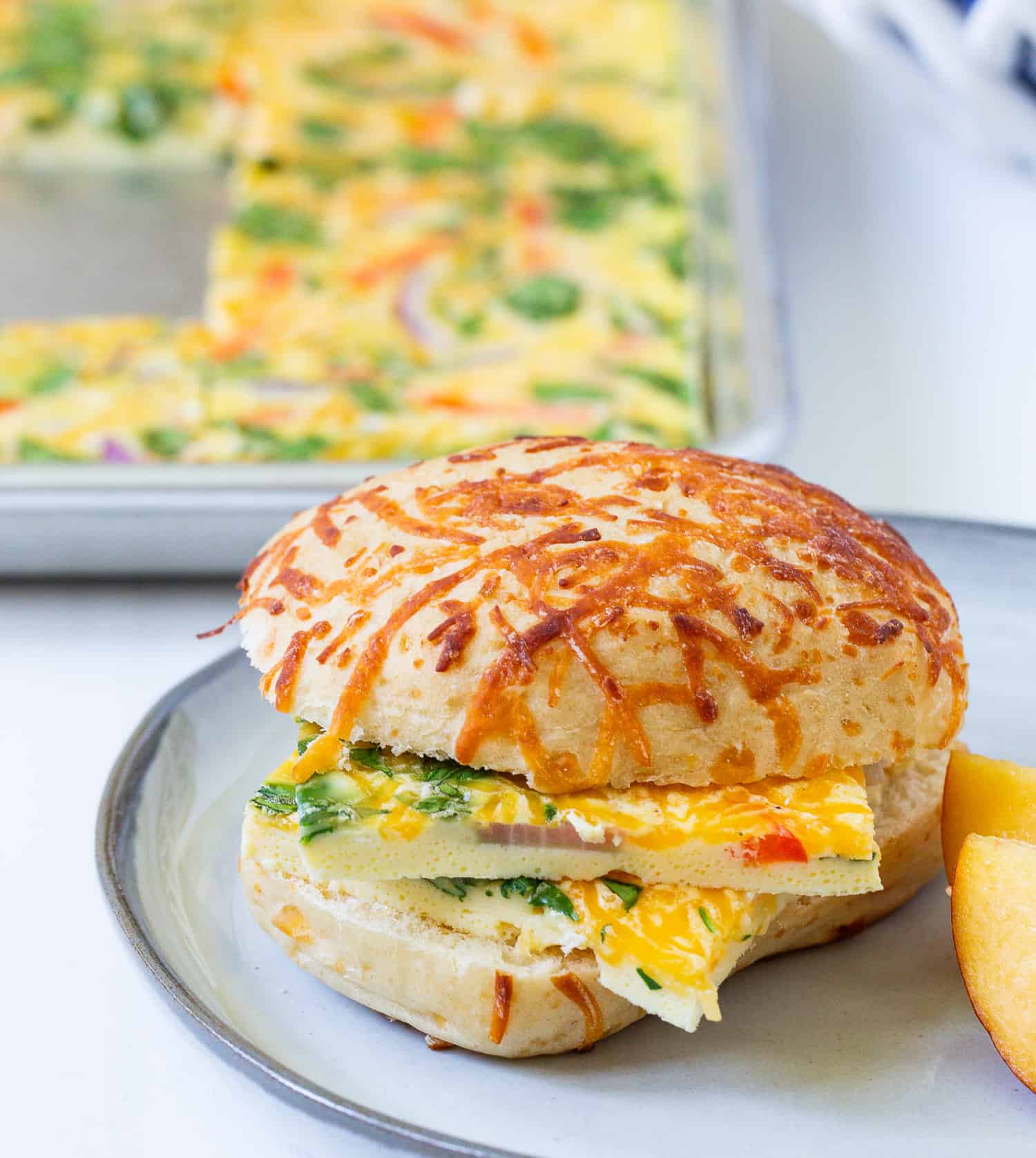 Sheet pan eggs served on a sliced cheese topped bun.