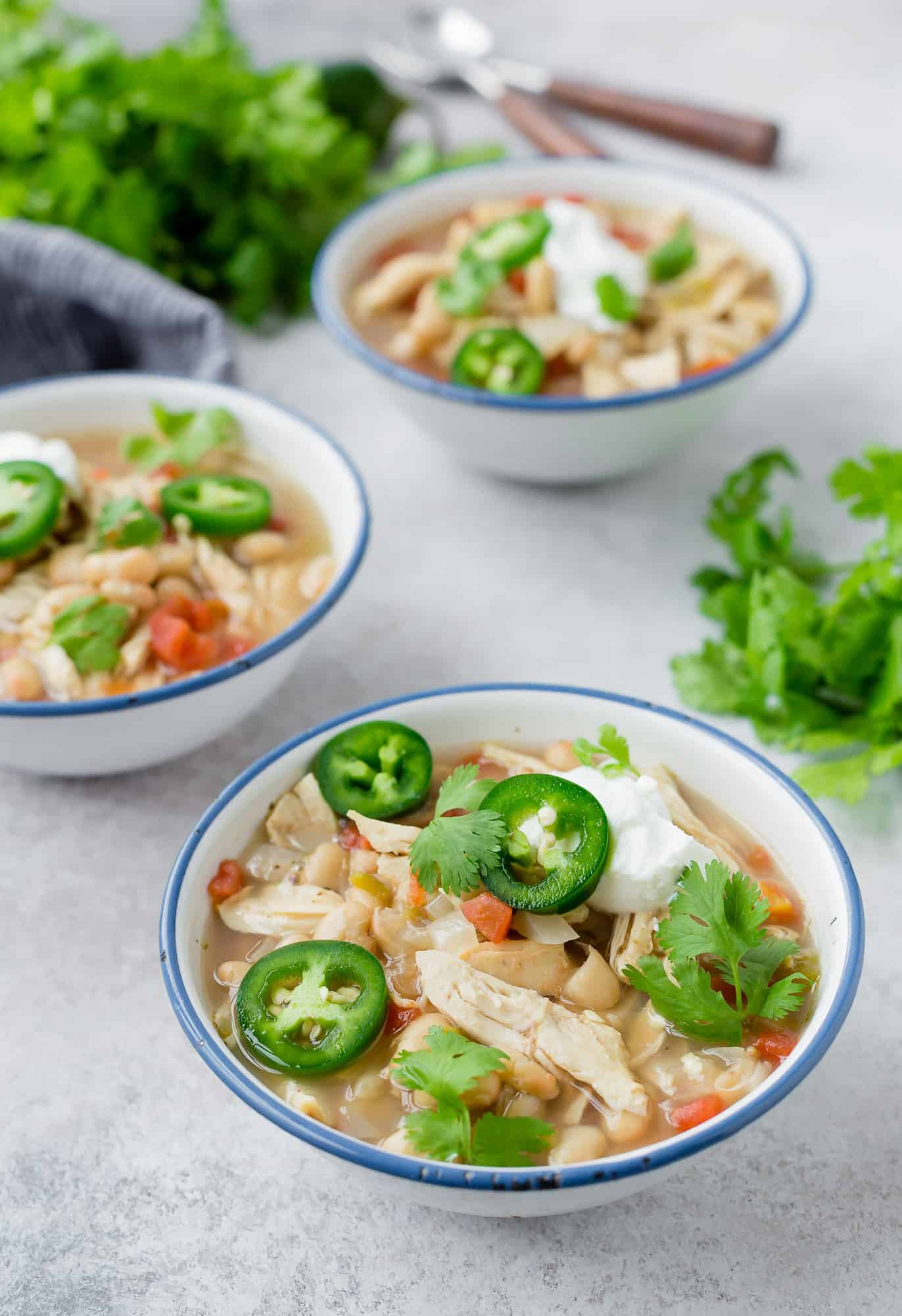 Chicken chili in bowls topped with cilantro and jalapeño. 