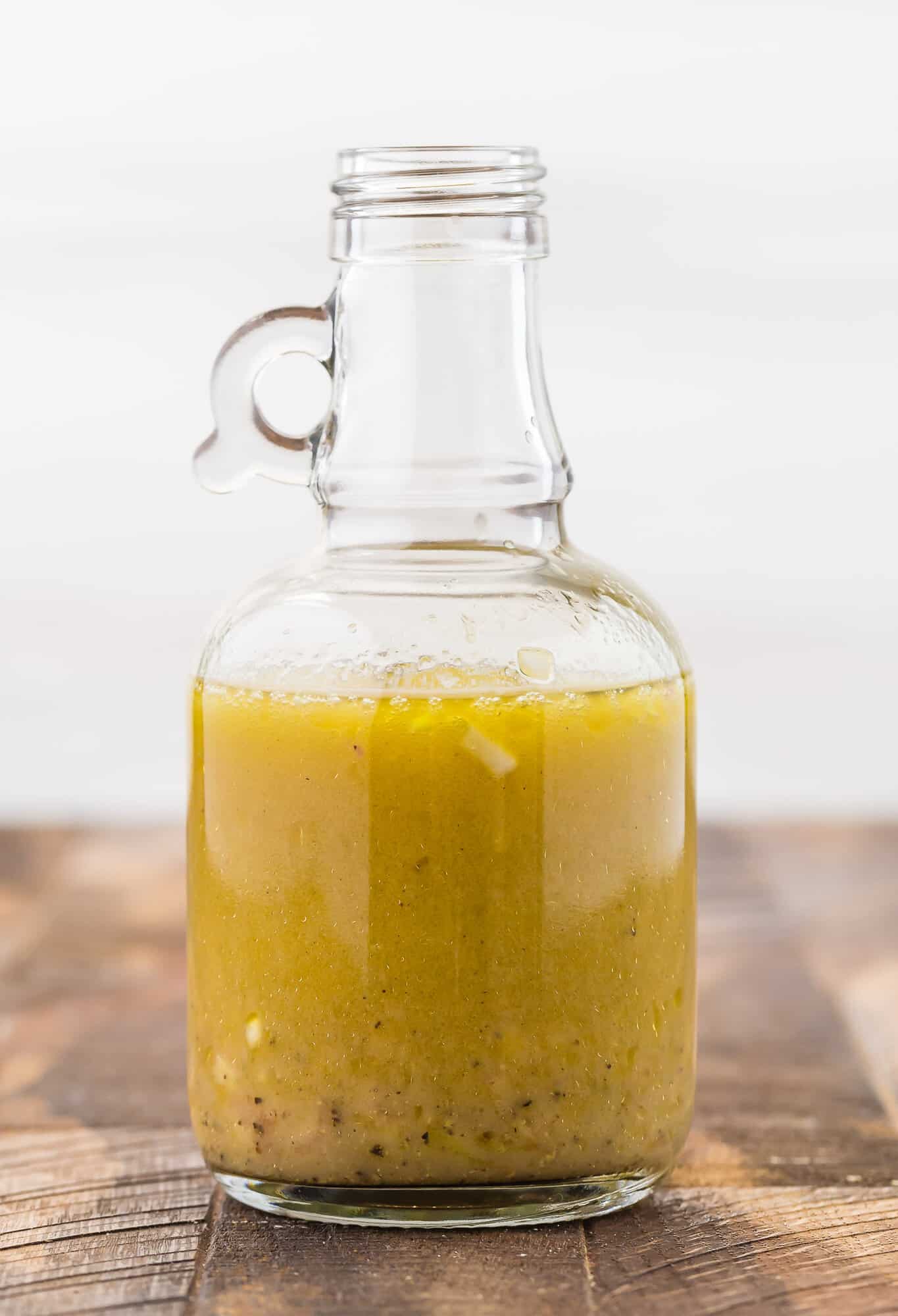 Salad dressing in a small jar on a wooden surface.