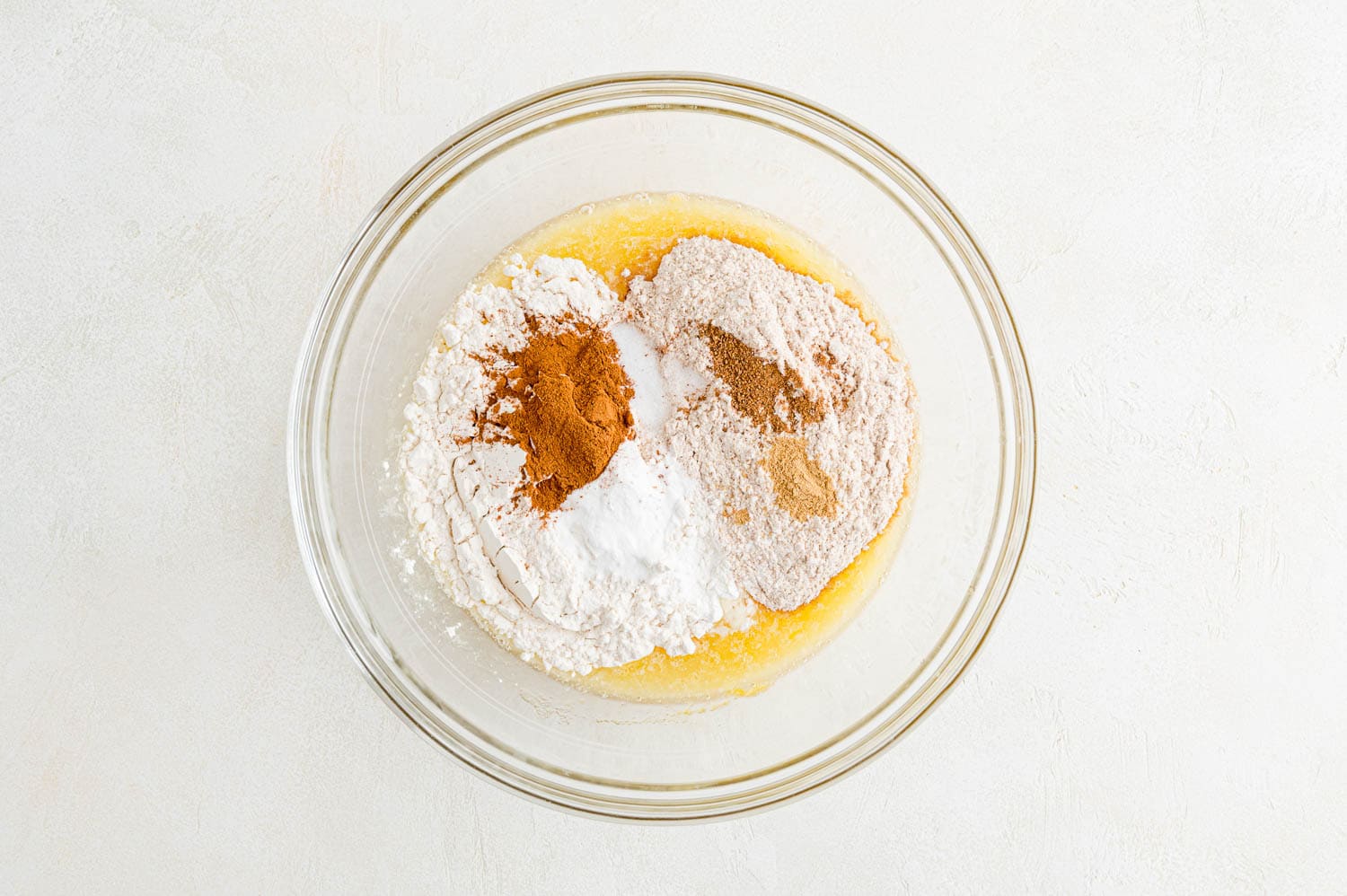 Dry ingredients on top of wet ingredients in a glass bowl, not yet stirred in.