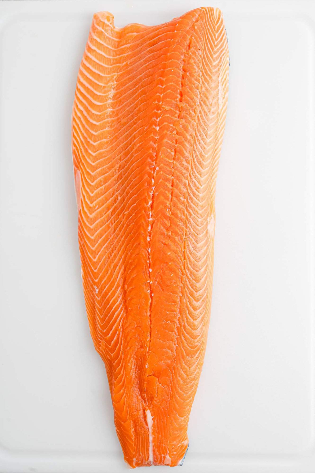 Overhead view of a whole side of salmon laid out on a white countertop.