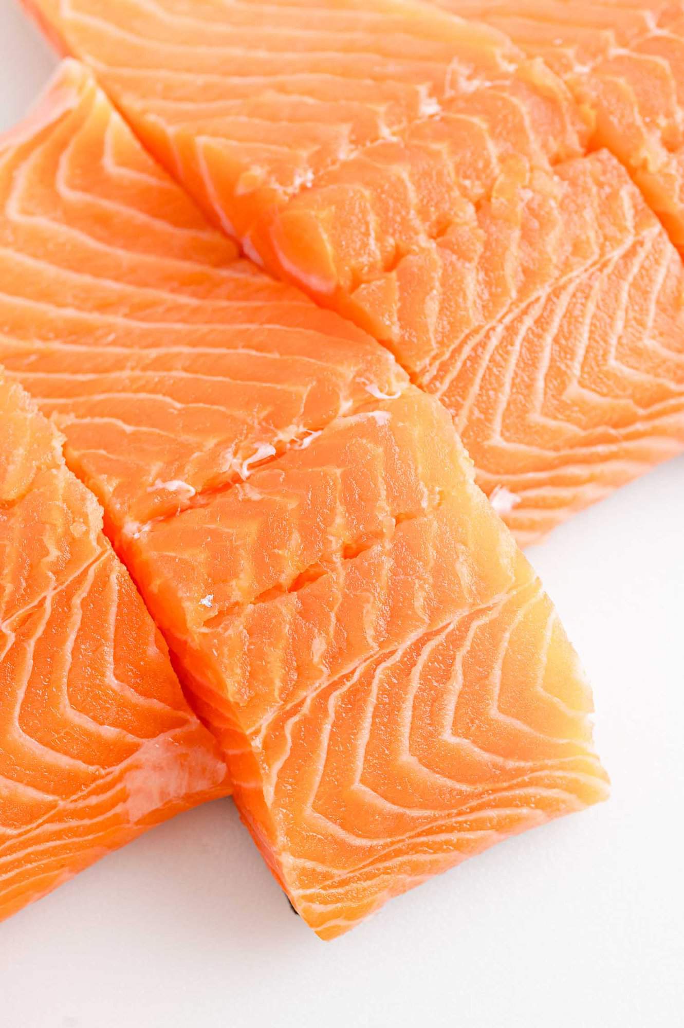 Close up of uncooked salmon filets on a white countertop.