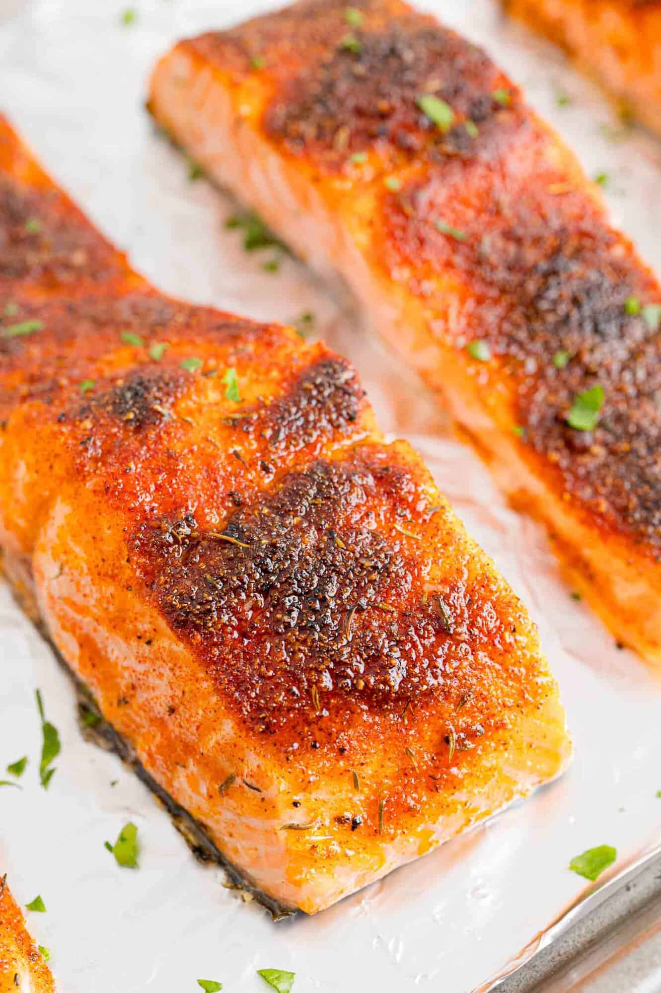 Close up of broiled salmon filets on a foil-lined baking sheet.