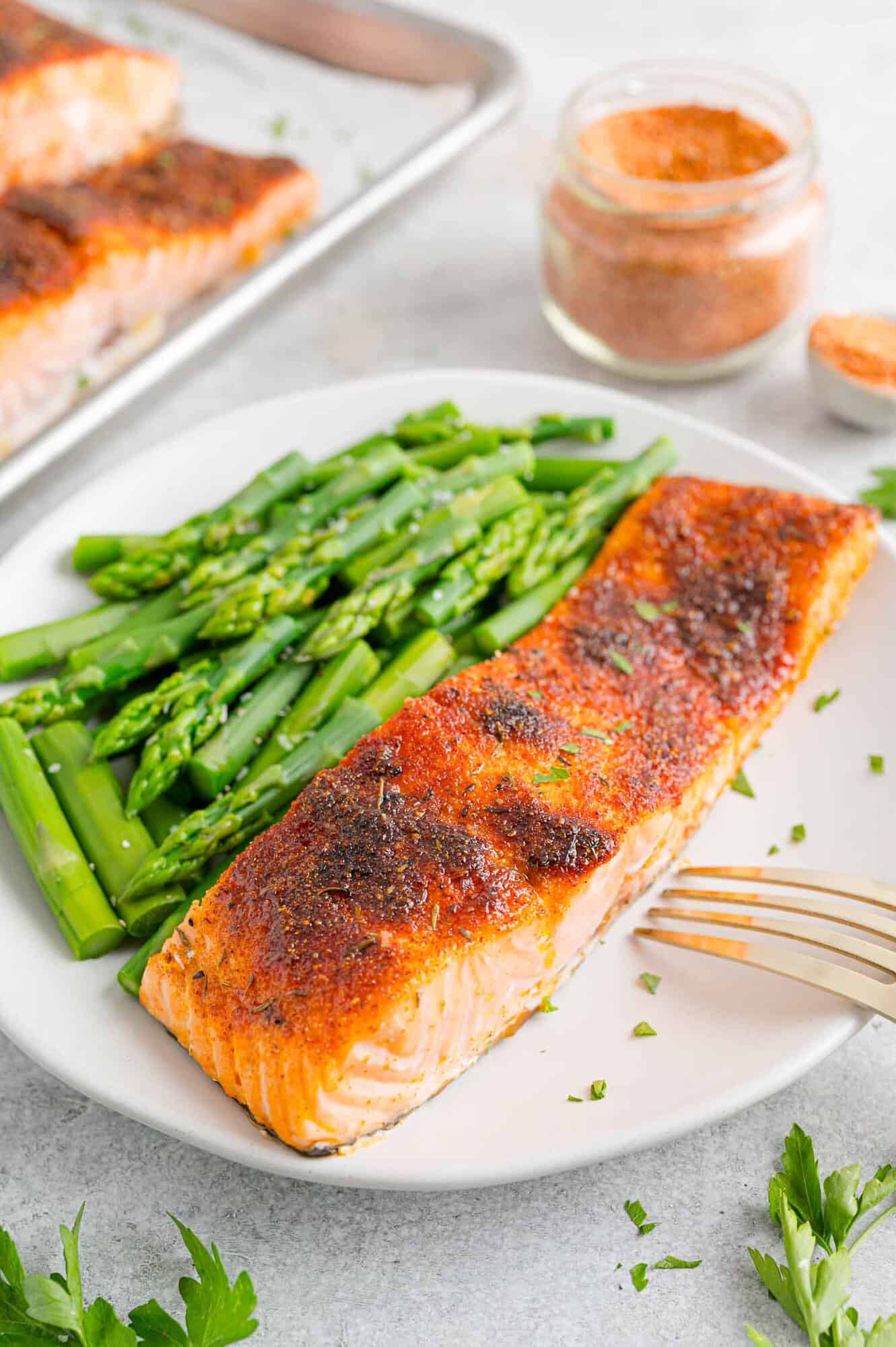 A broiled salmon filet with a side of green beans on a white plate.