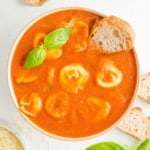 Crockpot tomato soup with cheese tortellini, garnished with fresh basil.