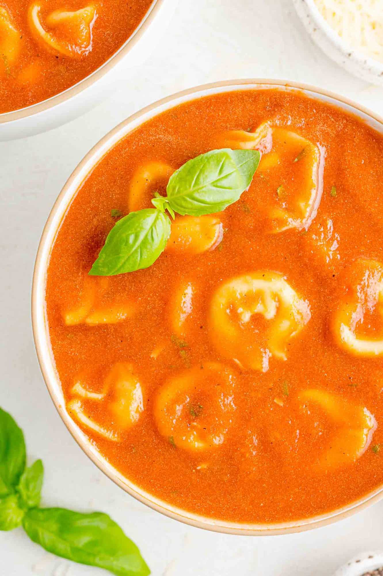 Crockpot tomato soup with tortellini, garnished with fresh basil.