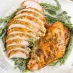 Herb roasted turkey breast, half sliced, half not sliced, on platter.