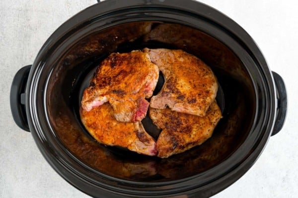 Seared pork chops inside the slow cooker.