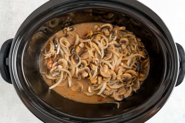 Mushroom and onion gravy ingredients dumped over top of the seared pork chops in the slow cooker.