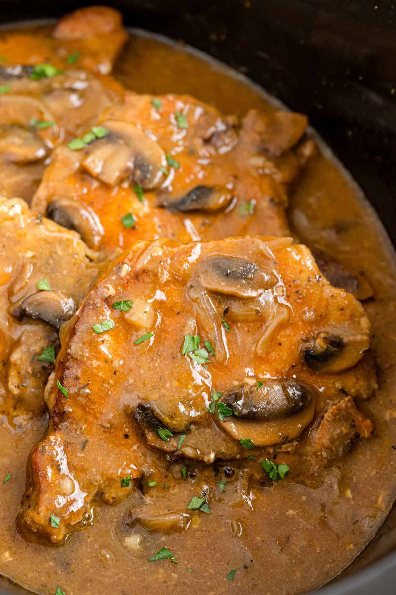 Pork chops covered in mushroom and onion gravy inside the slow cooker.