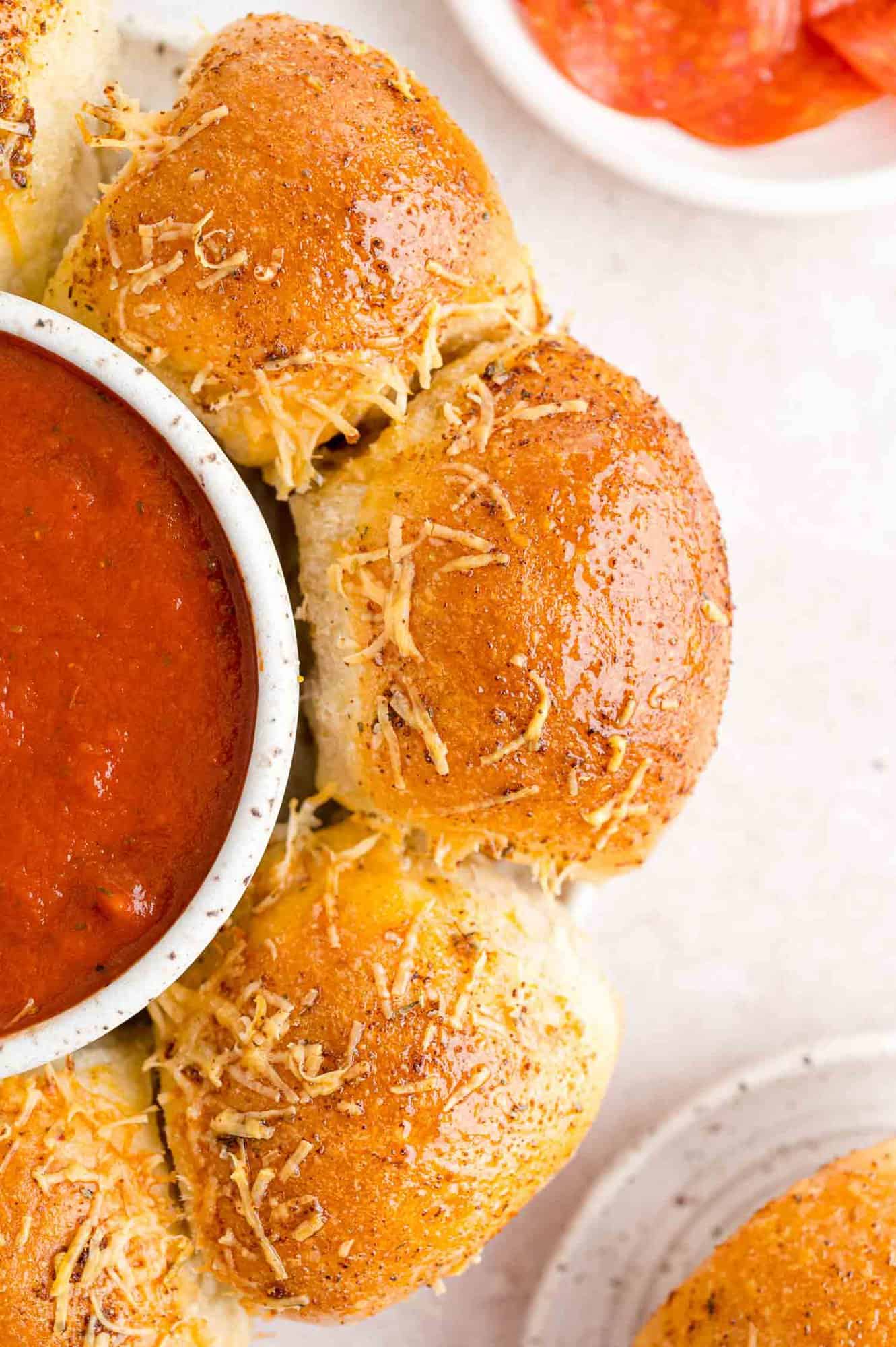 Stuffed pizza bites arranged around bowl of pizza sauce.