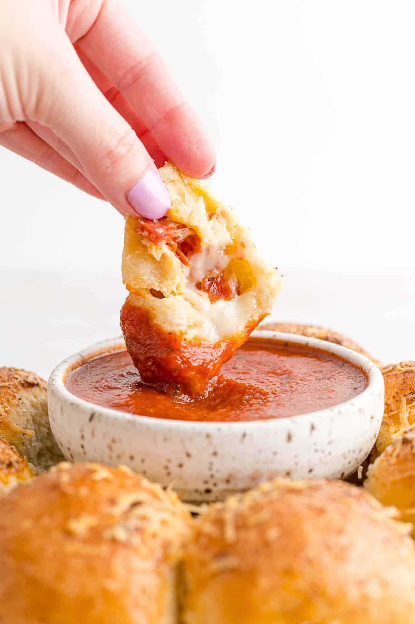 Pizza bite being dipped into sauce.