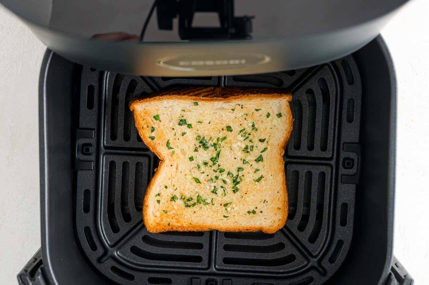Close up overhead view of a slice of toasted Texas toast garlic bread inside the air fryer.