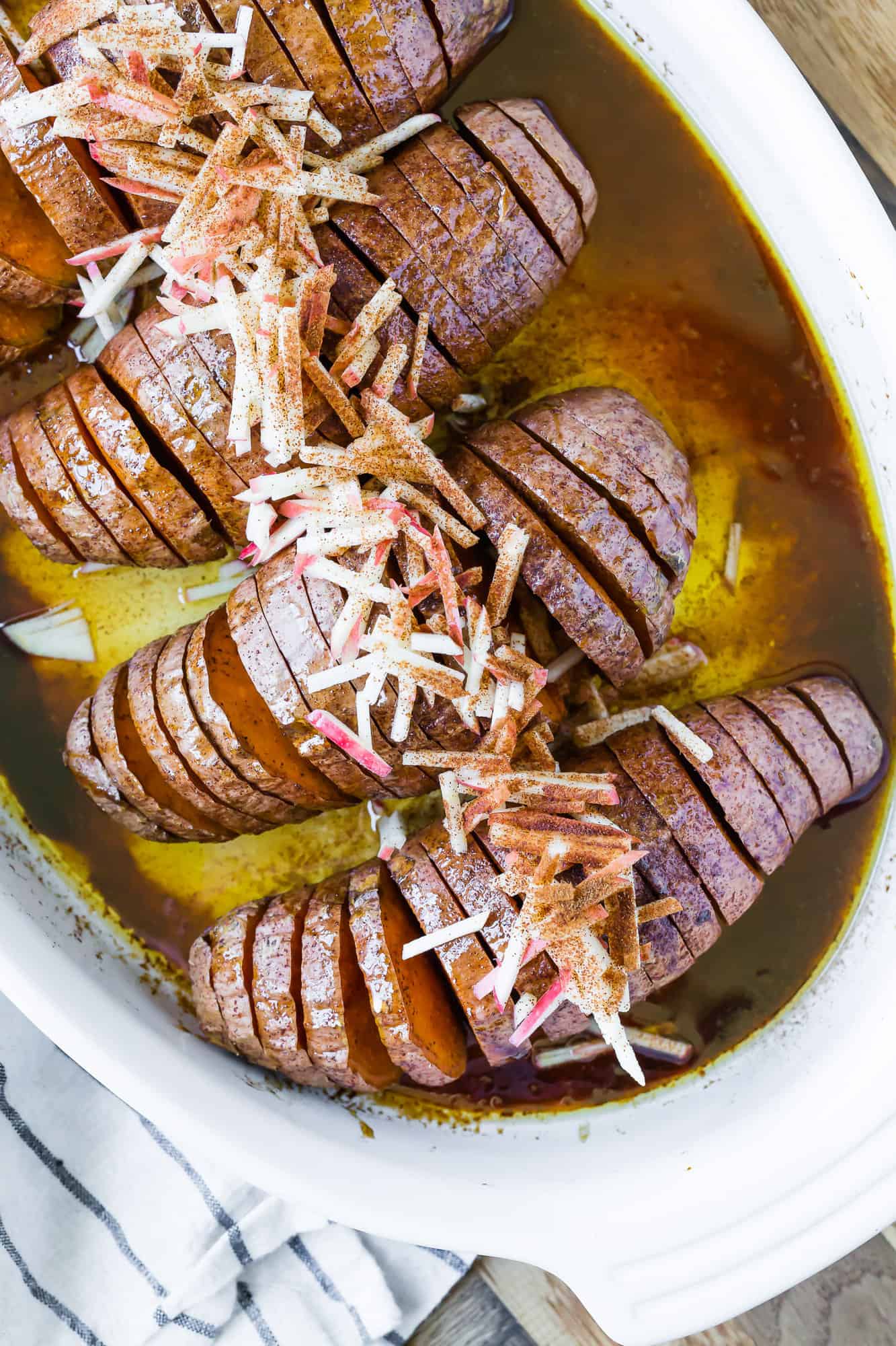 Overhead view of sweet potatoes in a pan with a cinnamon sugar butter sauce.