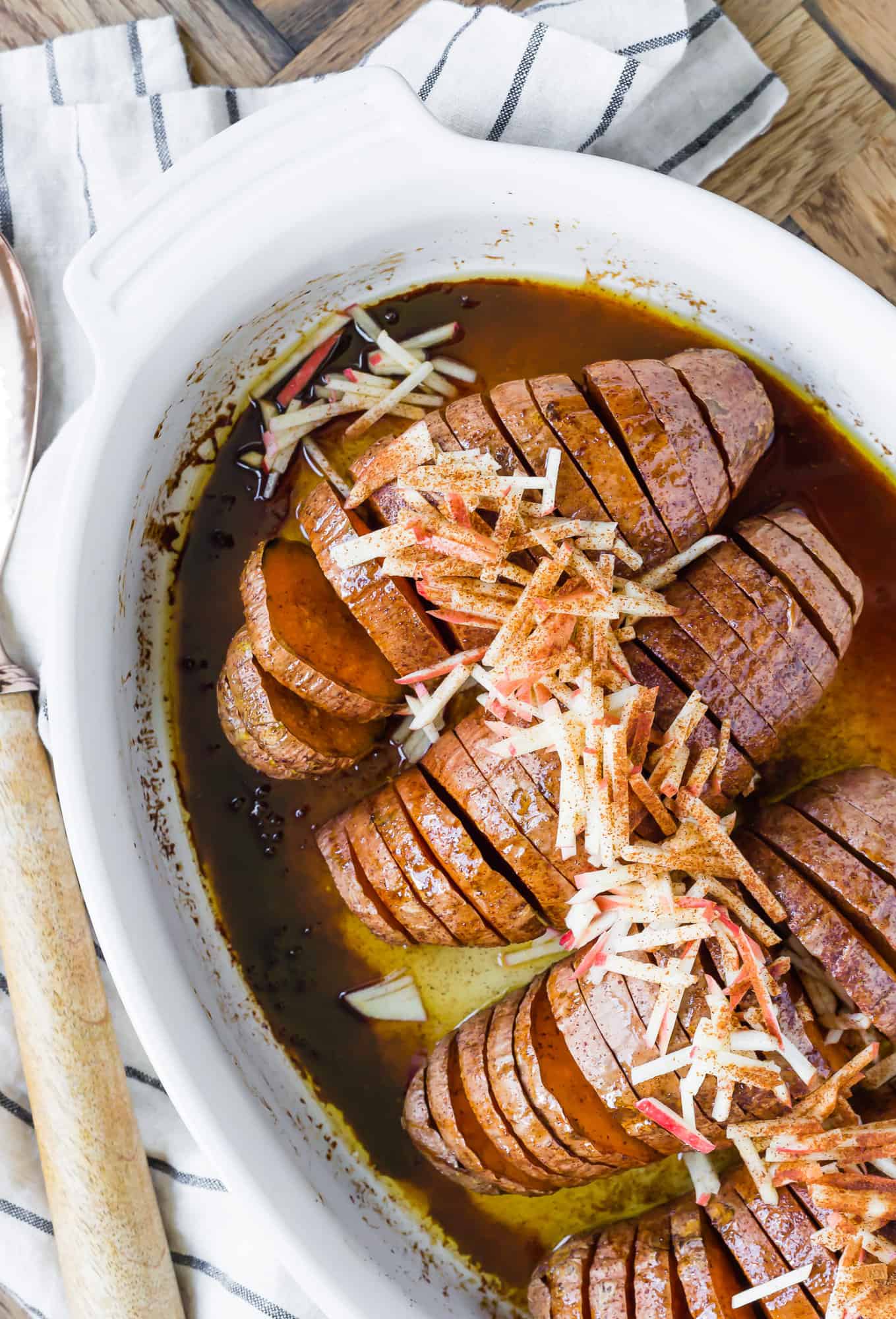 Sweet potatoes, cut in a hasselback style, in a white baking dish.