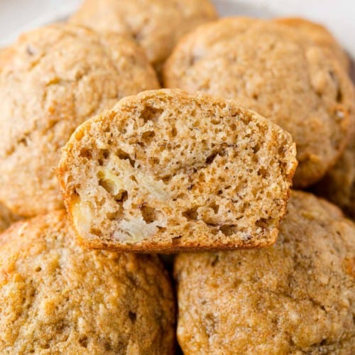 Pile of banana bread muffins, one cut to show texture.