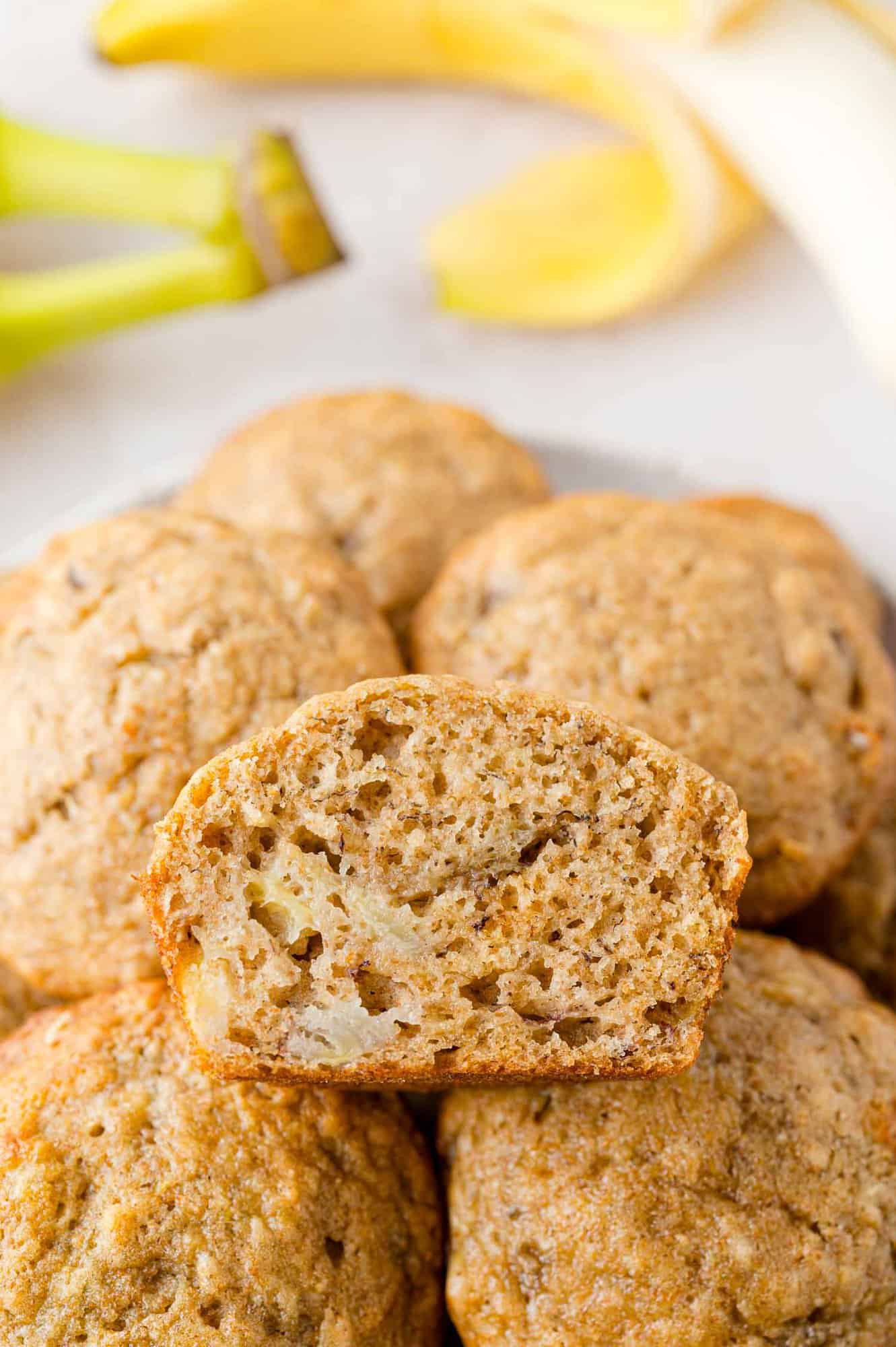 Pile of banana bread muffins, one cut to show texture.