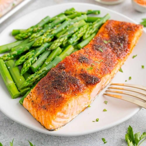 Broiled salmon on a white plate with steamed asparagus.