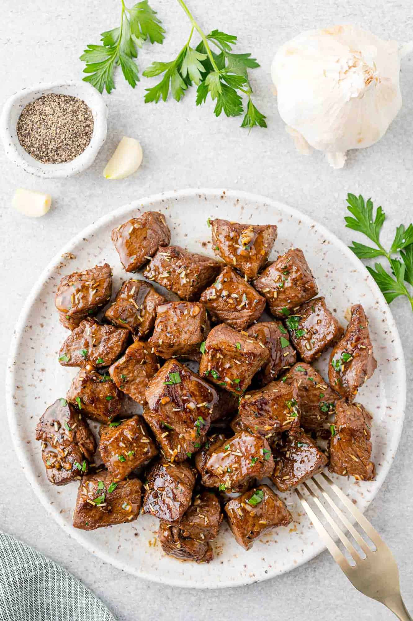 Garlic butter steak bites on a white serving platter.