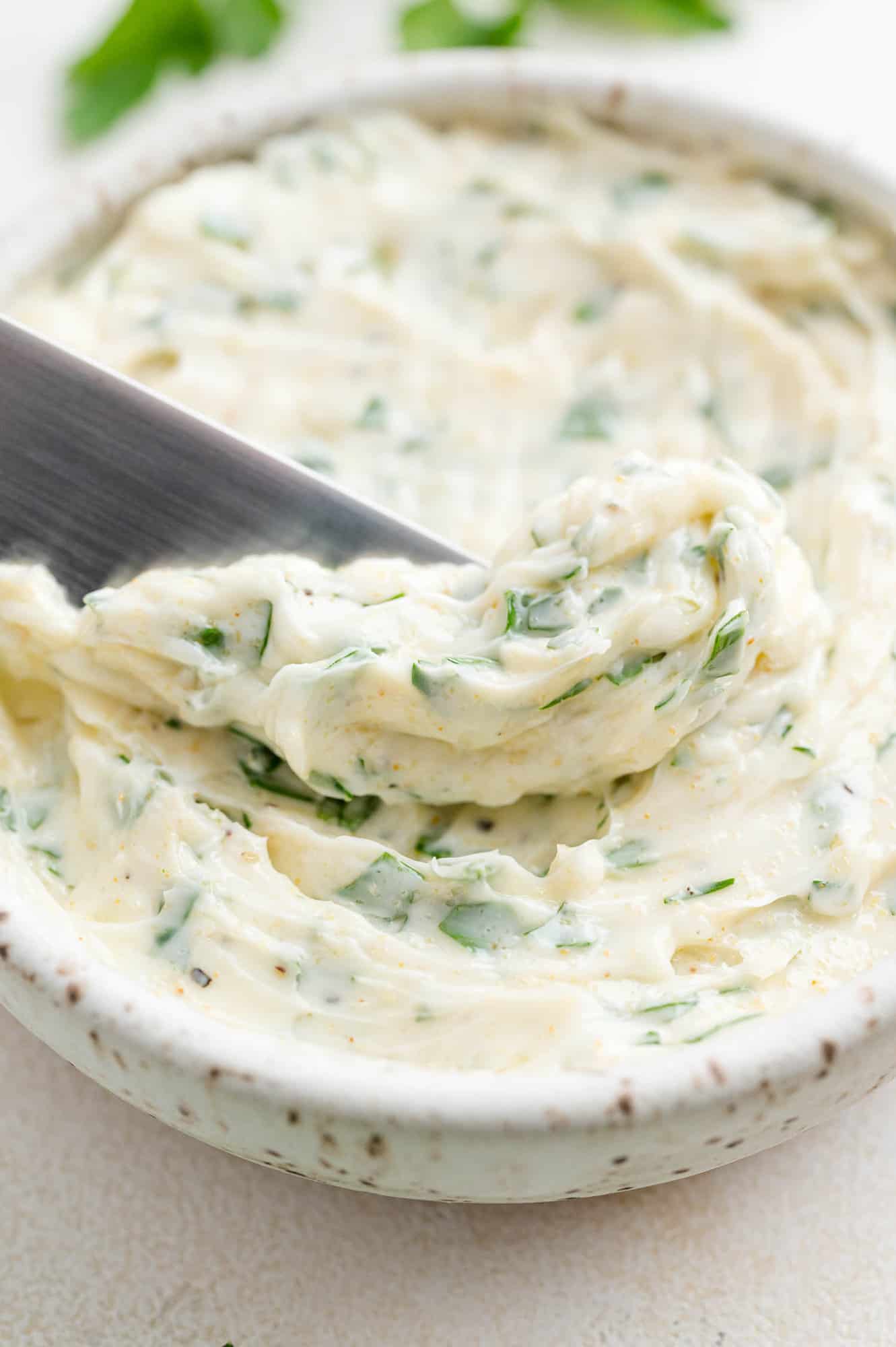 Garlic butter in a bowl and on a spreading knife.