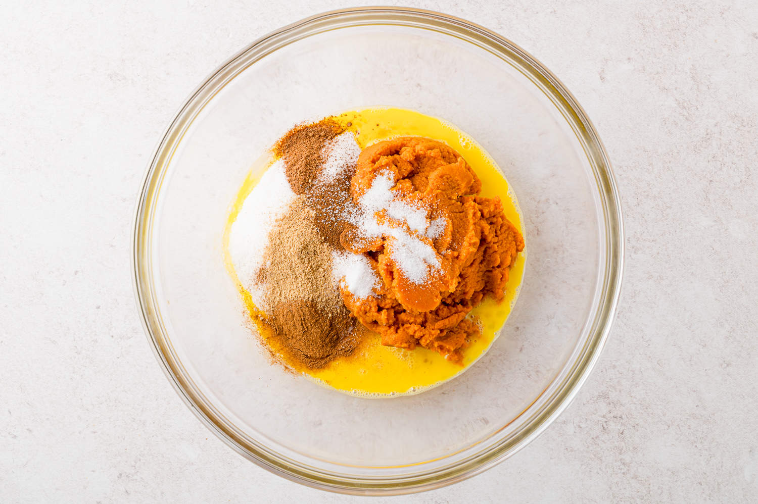 Pumpkin pie ingredients in a mixing bowl, not yet mixed.