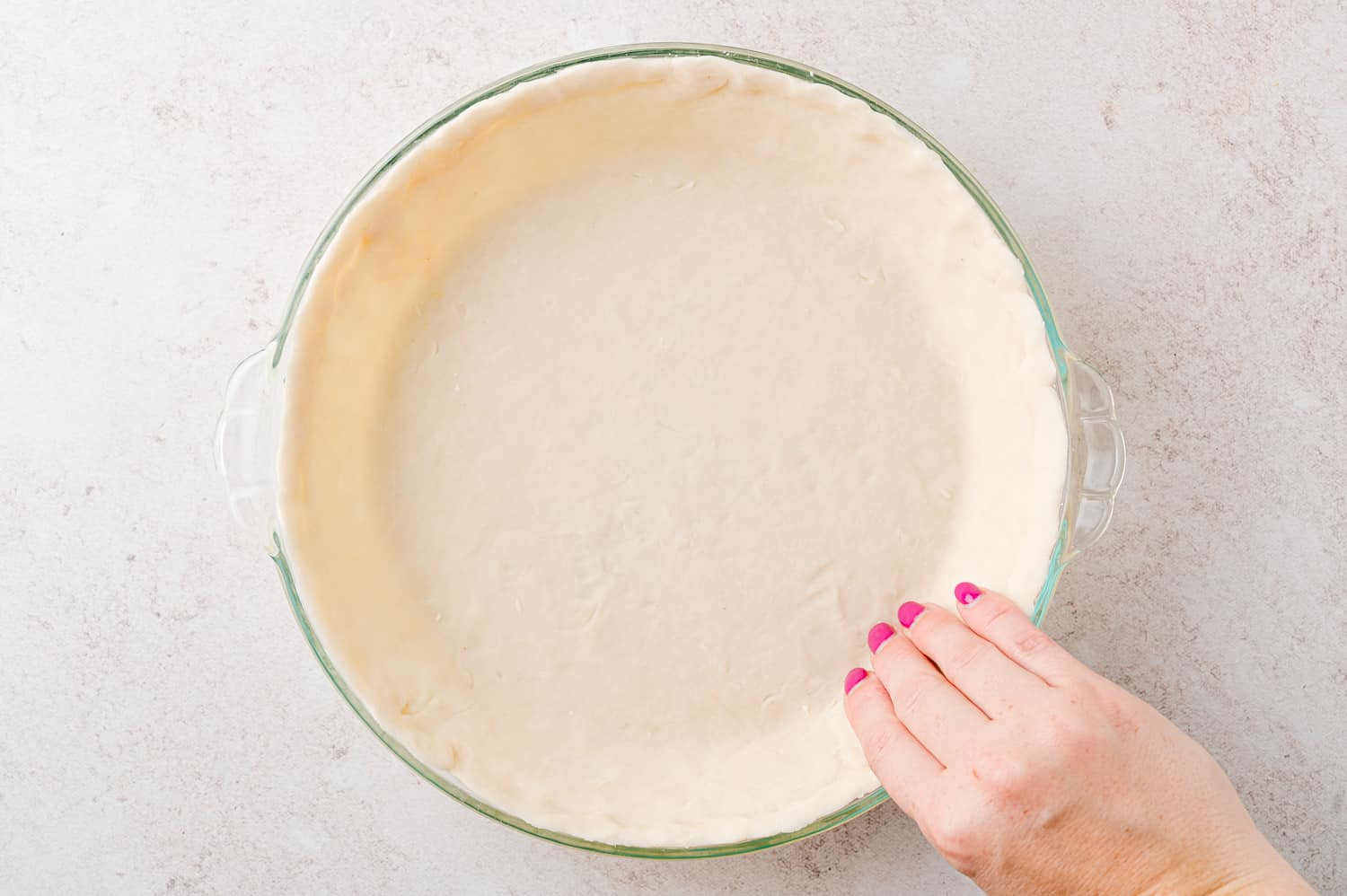 Pie crust being pressed into pie pan.
