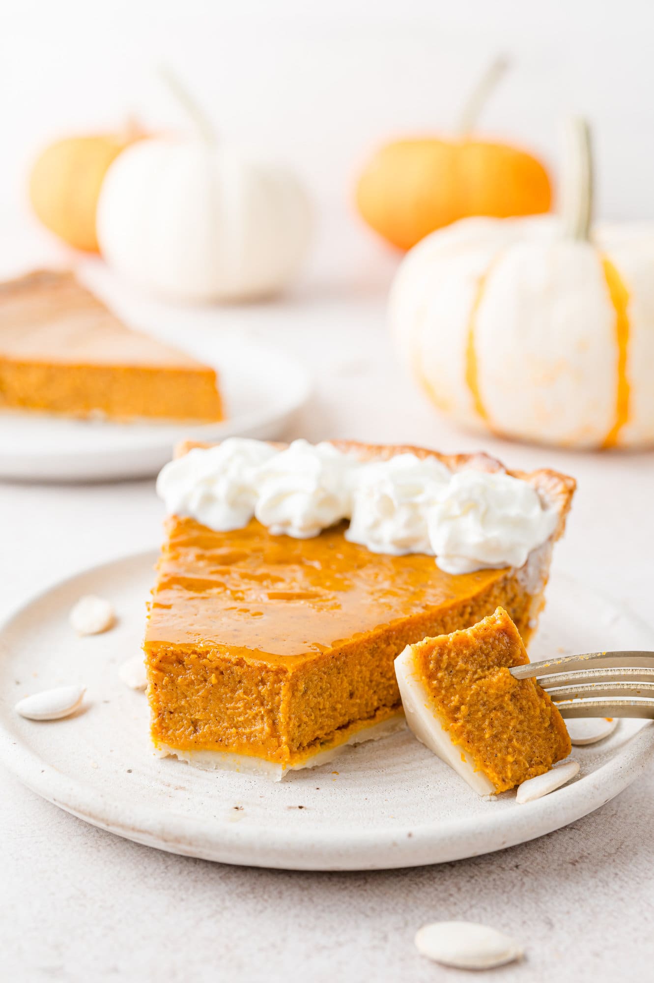 Slice of pumpkin pie with whipped cream, one bite removed.