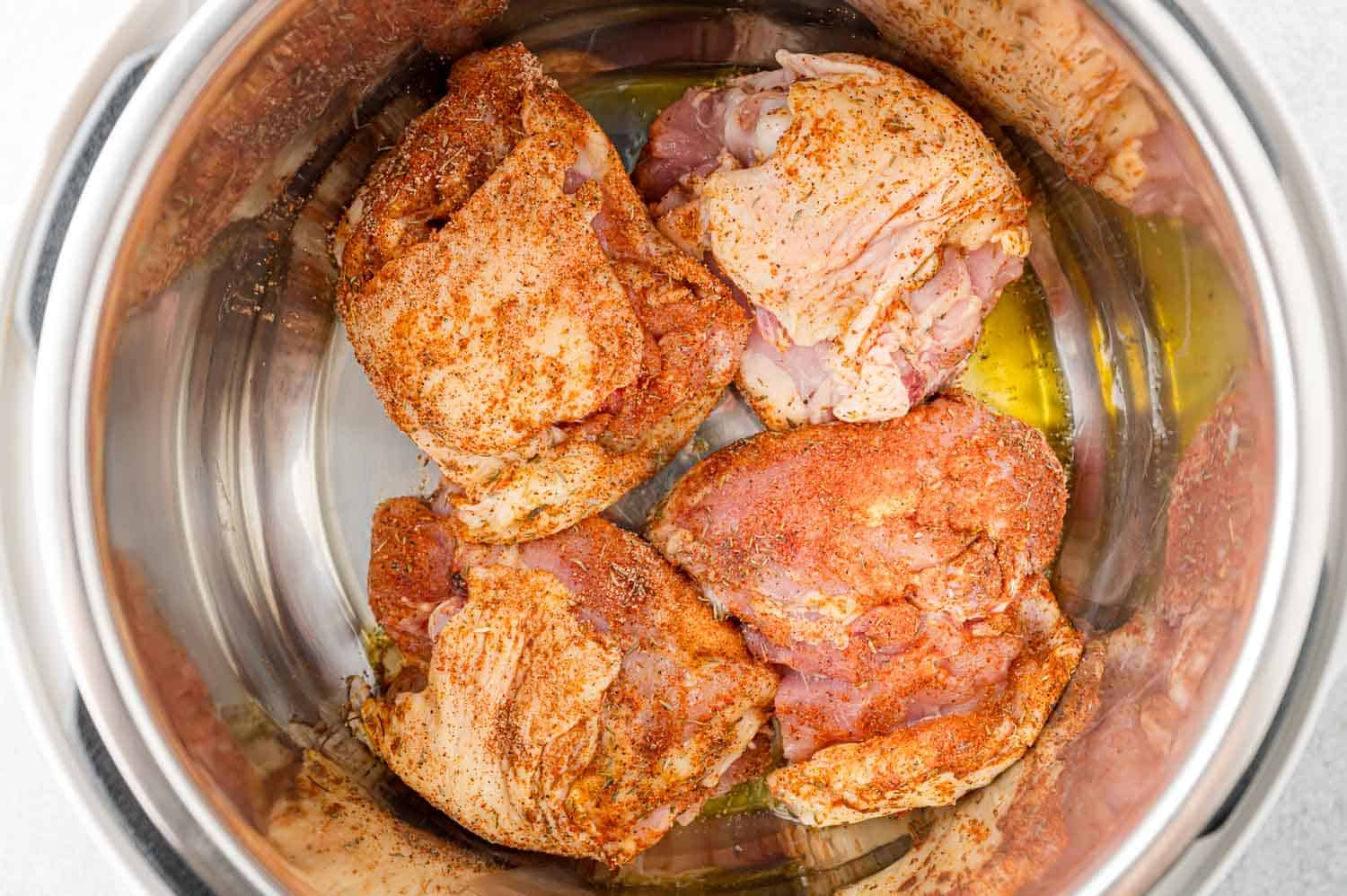 Chicken thighs being browned on the first side in the Instant Pot.
