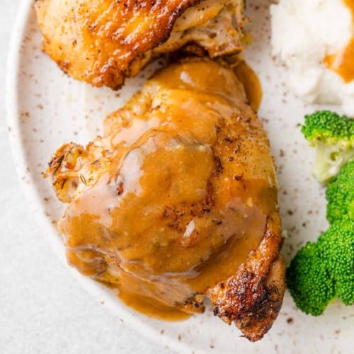 Instant pot chicken thighs on a plate with broccoli and mashed potatoes.