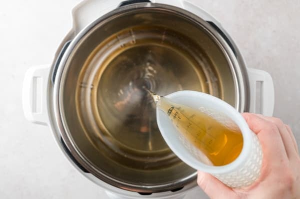 Chicken broth being added to an Instant Pot.